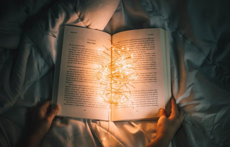 Storytelling Heart - person holding string lights on opened book