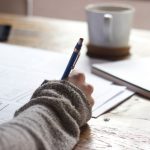 Mentorship Guidance - person writing on brown wooden table near white ceramic mug