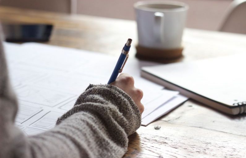 Mentorship Guidance - person writing on brown wooden table near white ceramic mug