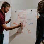 Economics Chart - man drawing on dry-erase board