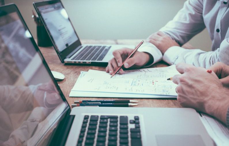 Growth Strategy - person holding pencil near laptop computer