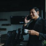 Success Measurement - smiling man holding cup and using smartphone