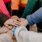 Community Engagement - person in red sweater holding babys hand