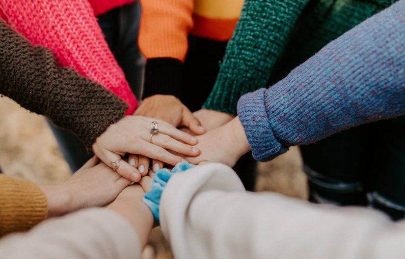 Community Engagement - person in red sweater holding babys hand