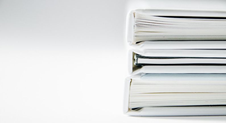 Ethics Book - A stack of thick folders on a white surface