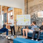 Inspiring Leaders - three men sitting while using laptops and watching man beside whiteboard