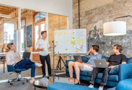 Inspiring Leaders - three men sitting while using laptops and watching man beside whiteboard