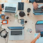 Technology Impact - people sitting down near table with assorted laptop computers