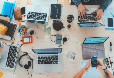 Technology Impact - people sitting down near table with assorted laptop computers