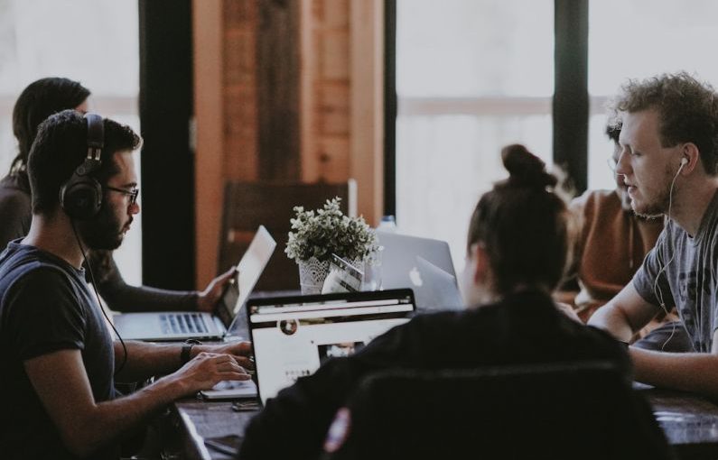 Collaboration Team - selective focus photography of people sits in front of table inside room