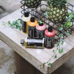 Branding Eco - five assorted bottles on brown table beside two pineapples
